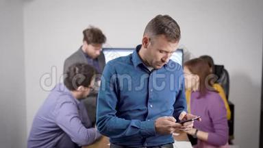 男人在智能手机上打短信，<strong>站在</strong>办公室会议室，<strong>商务人士</strong>在交流